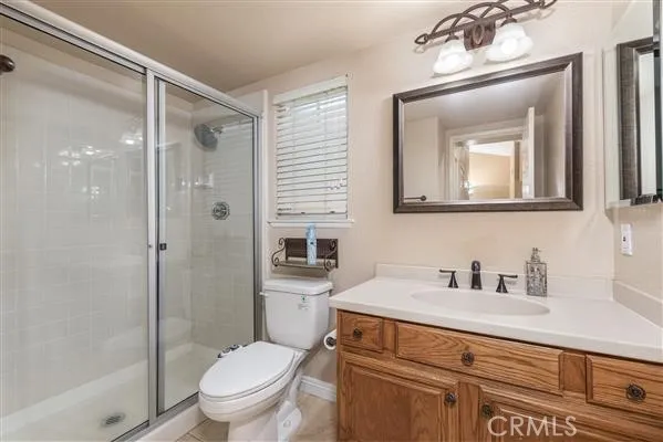 a bathroom with a toilet a sink a glass door a shower a mirror and vanity