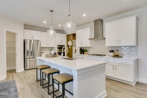 a kitchen with stainless steel appliances a stove a sink a refrigerator a center island and chairs