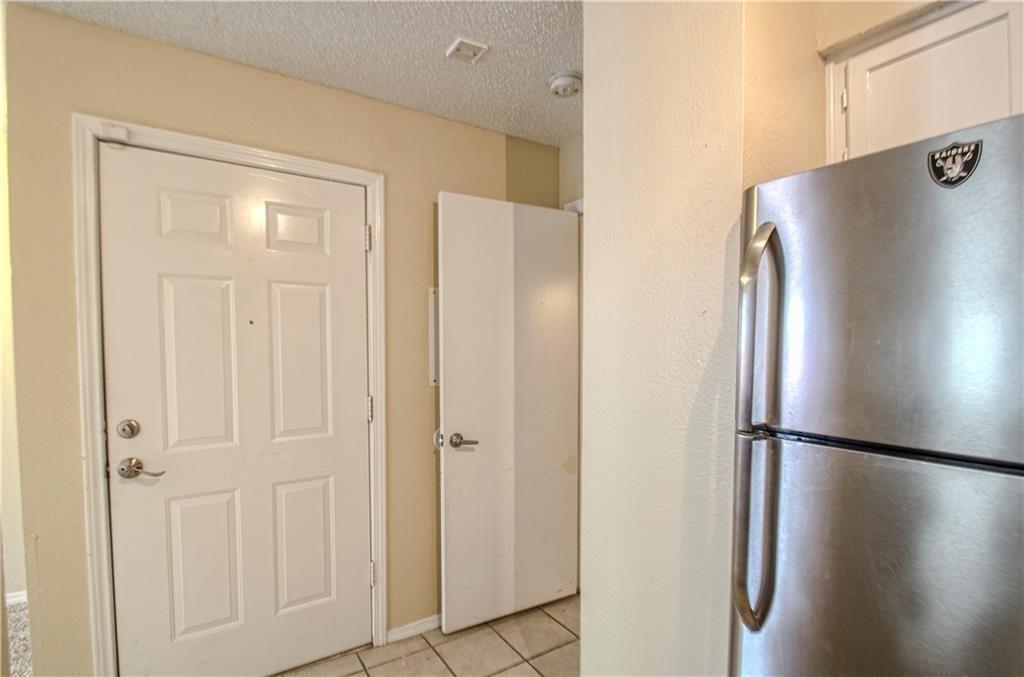 9835 Walnut Street, Unit 202 Dallas, TX 75243 - Photo 13 of 19 Entry area featuring a six-panel door, stainless steel refrigerator, textured walls, and tile flooring