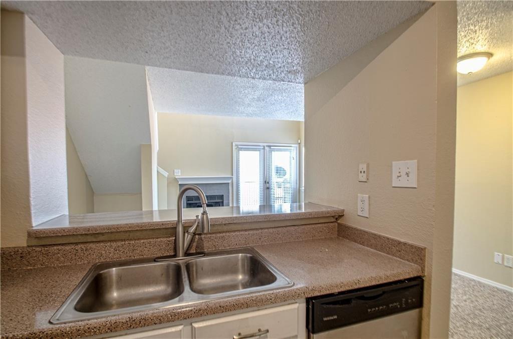 9835 Walnut Street, Unit 202 Dallas, TX 75243 - Photo 14 of 19 Kitchen sink area featuring a dual-basin stainless steel sink with a modern faucet, set into a speckled countertop