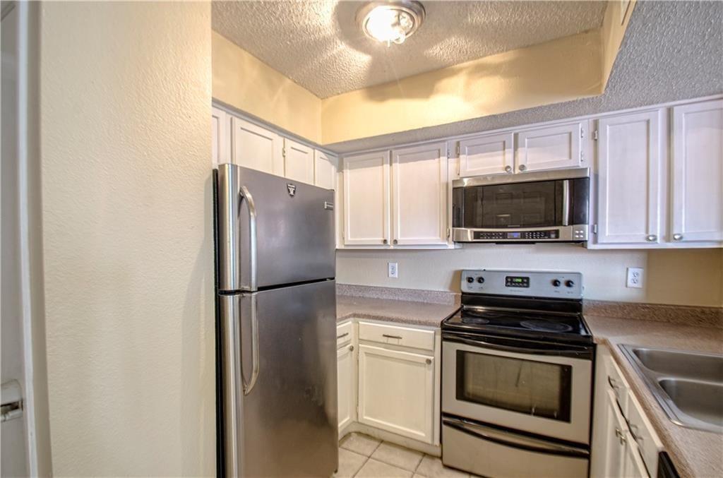 9835 Walnut Street, Unit 202 Dallas, TX 75243 - Photo 3 of 19 Kitchen featuring white cabinetry, stainless steel appliances, a built-in microwave, and a double basin sink