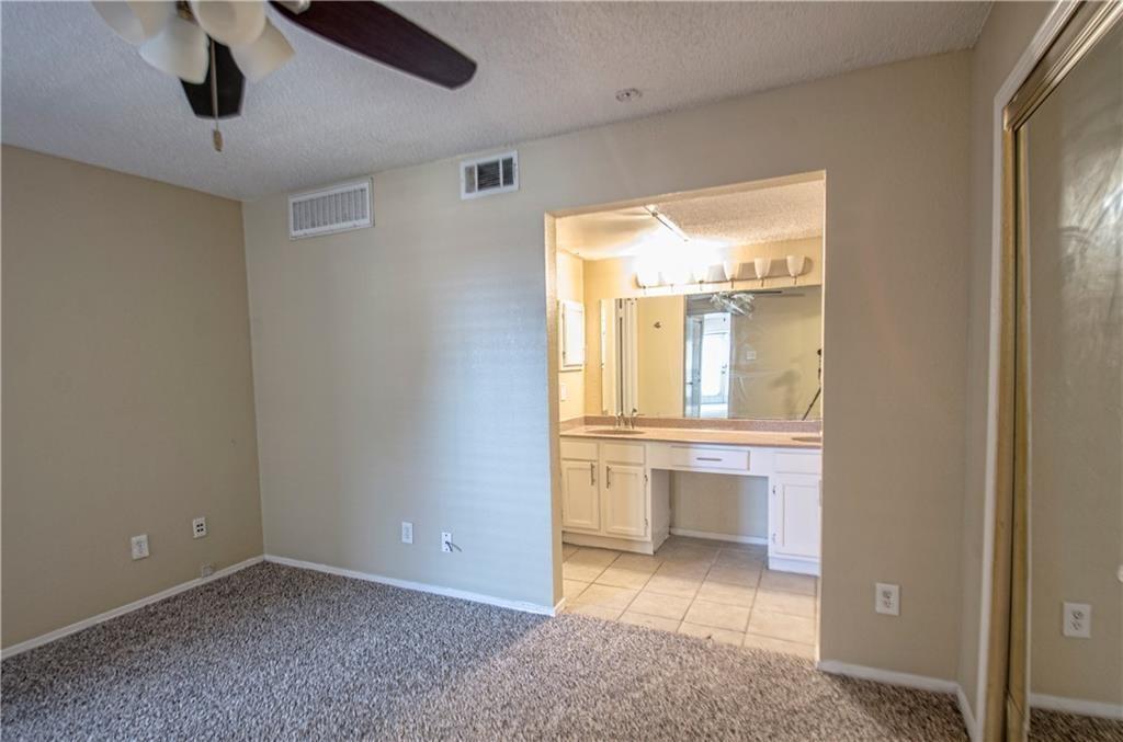 9835 Walnut Street, Unit 202 Dallas, TX 75243 - Photo 4 of 19 Spacious bedroom with neutral-toned walls and plush carpeting, featuring a ceiling fan