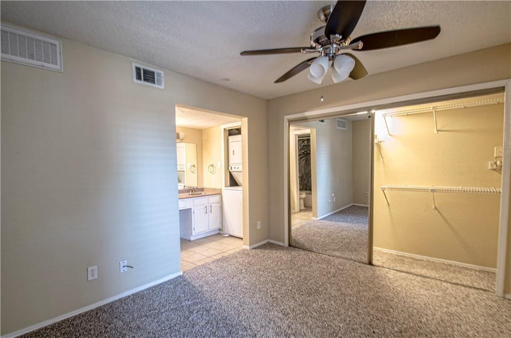 9835 Walnut Street, Unit 202 Dallas, TX 75243 - Photo 6 of 19 Carpeted room featuring a ceiling fan with integrated lighting, mirrored sliding closet doors, and wire shelving