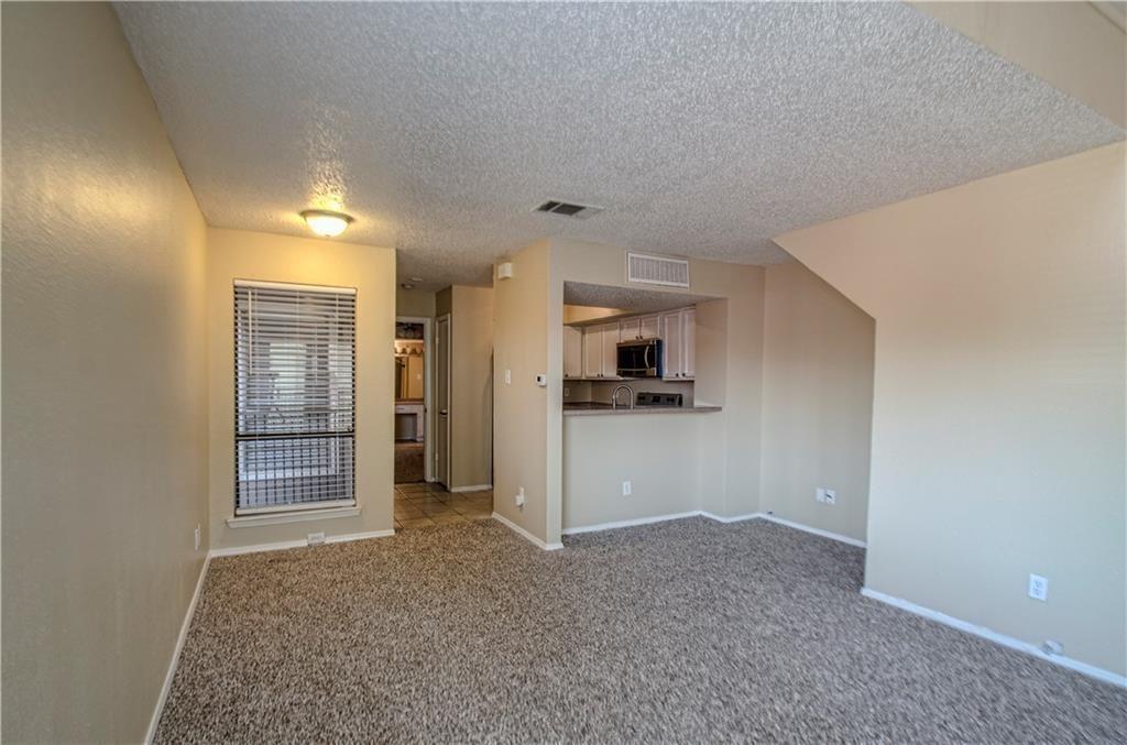 9835 Walnut Street, Unit 202 Dallas, TX 75243 - Photo 9 of 19 Living area featuring a textured carpet, neutral wall tones, and a window with blinds