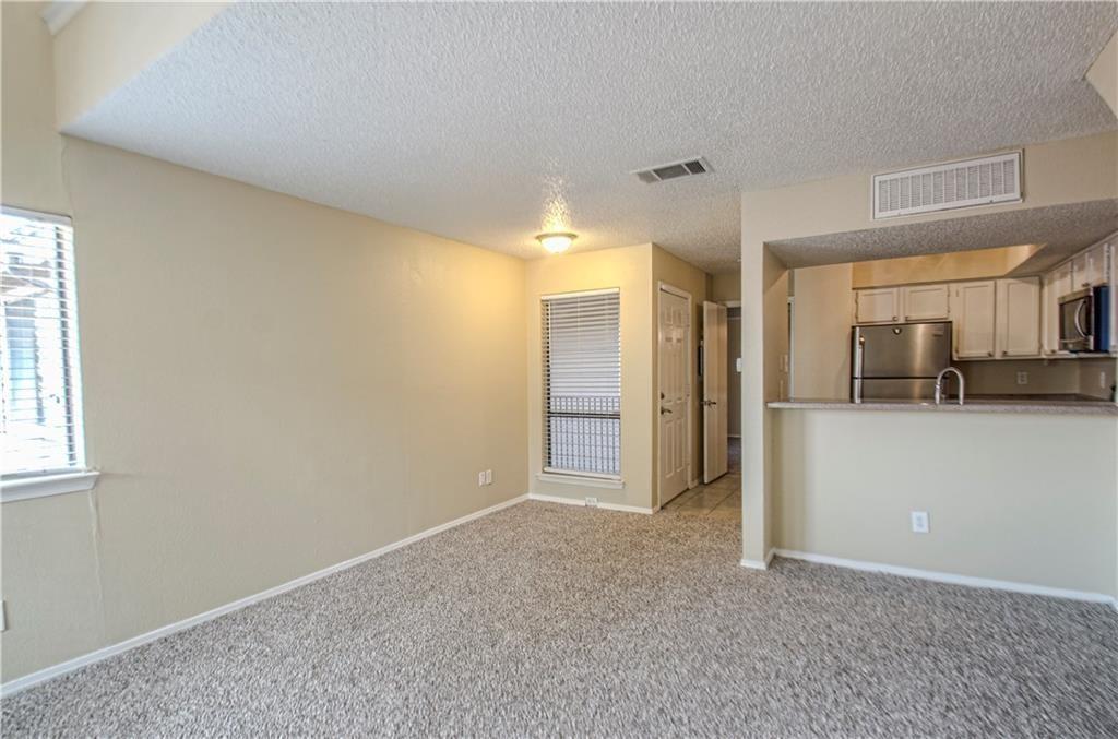 9835 Walnut Street, Unit 202 Dallas, TX 75243 - Photo 10 of 19 Living area featuring neutral-toned walls, textured ceiling, and patterned carpet flooring