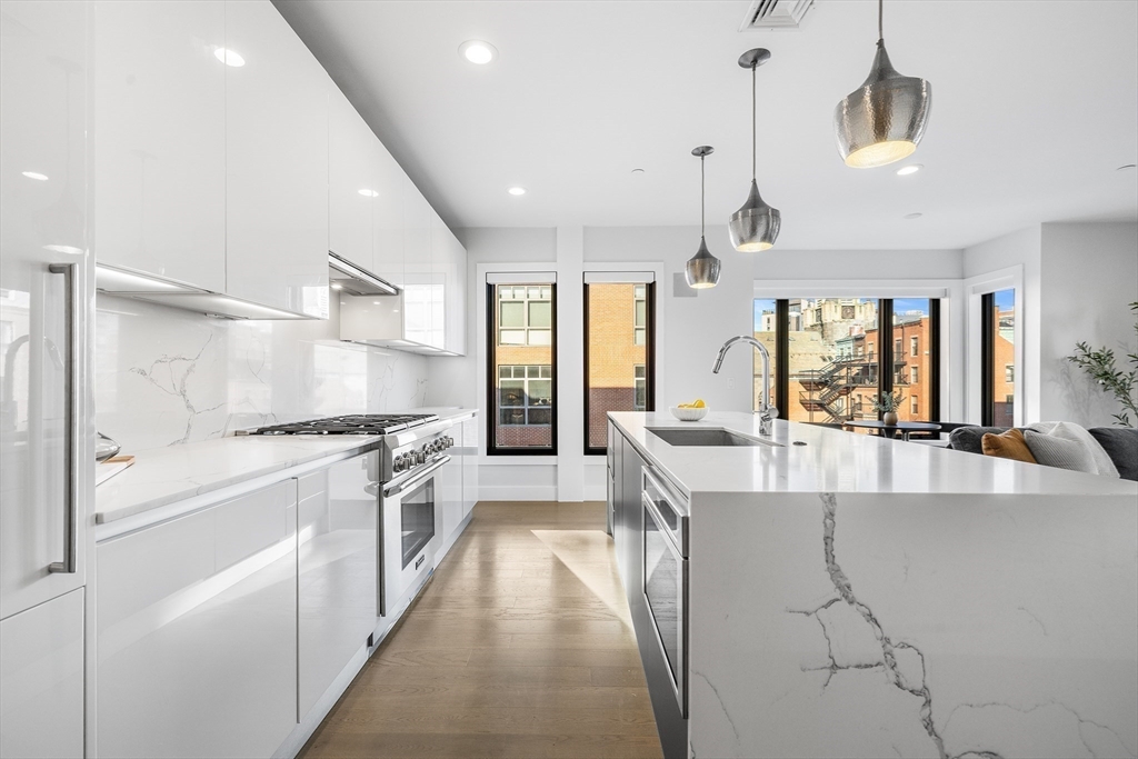 39 A Street, Unit 19 Boston, MA 02127 - Photo 2 of 24 a large white kitchen with lots of counter top space a sink stainless steel appliances and cabinets