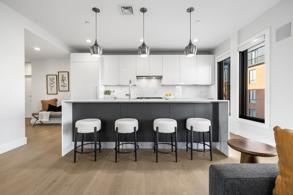 39 A Street, Unit 19 Boston, MA 02127 - Photo 9 of 24 a kitchen with stainless steel appliances granite countertop a kitchen island a table and chairs in it