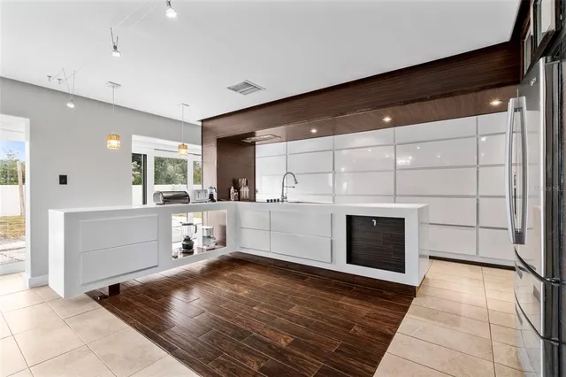 a view of a refrigerator in kitchen and an empty room