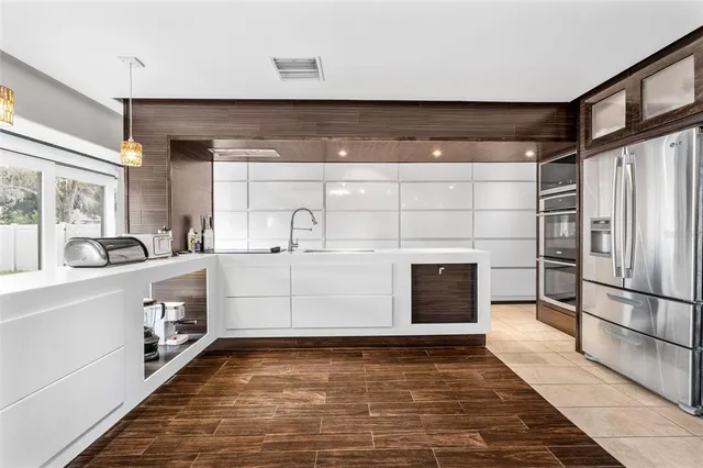 a kitchen with stainless steel appliances kitchen island granite countertop a refrigerator and a sink