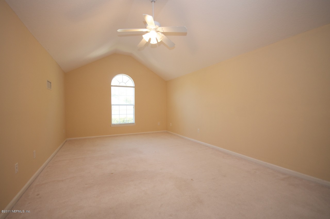 860 Mill Stream Road Ponte Vedra, FL 32082 - Photo 17 of 28 an empty room with a chandelier fan and windows