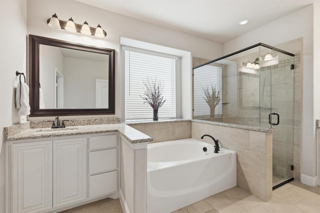 924 Timber Ridge Drive Justin, TX 76247 - Photo 22 of 32 Spacious bathroom featuring a built-in soaking tub, glass-enclosed shower, single vanity with light-toned countertop, and tile flooring
