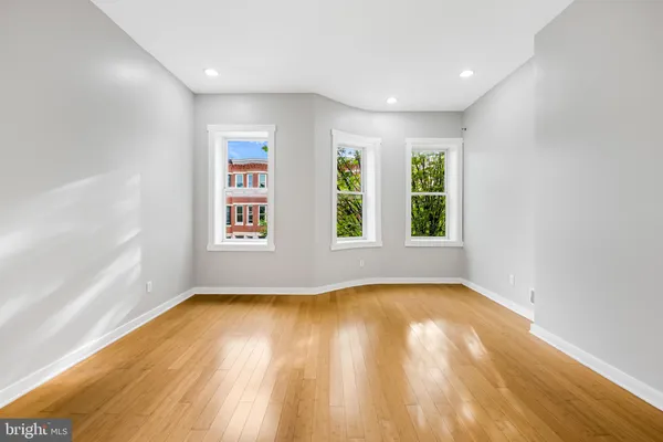 an empty room with wooden floor and windows