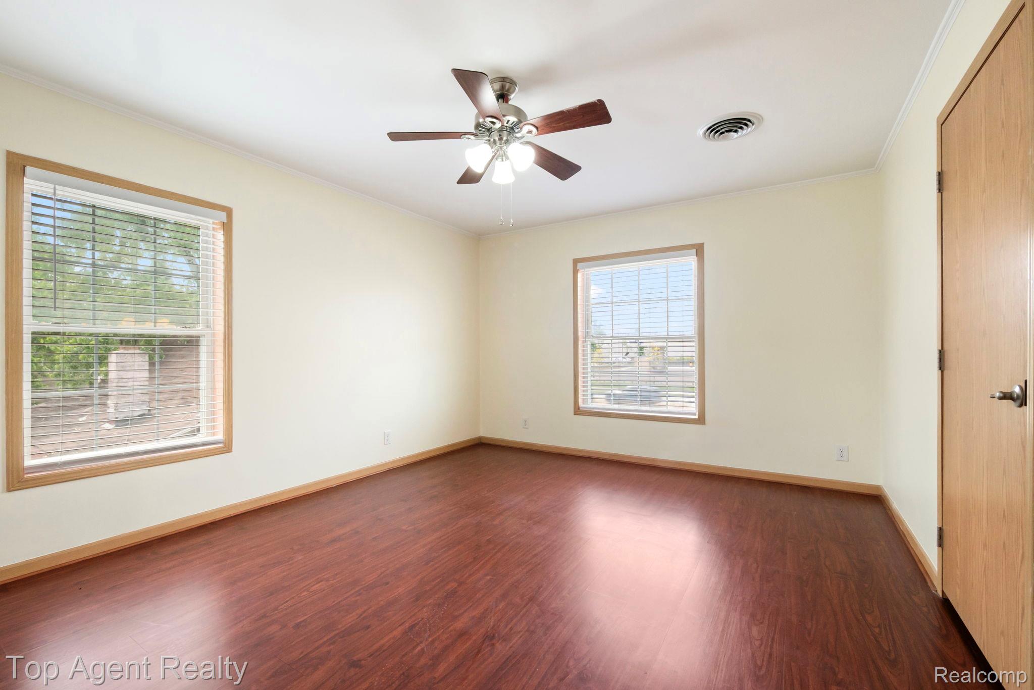 2018 John R Road Troy, MI 48083 - Photo 12 of 30 Empty room with crown molding, dark wood-style flooring, and ceiling fan