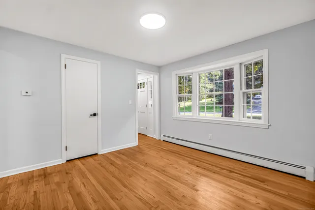 a view of an empty room with wooden floor and a window