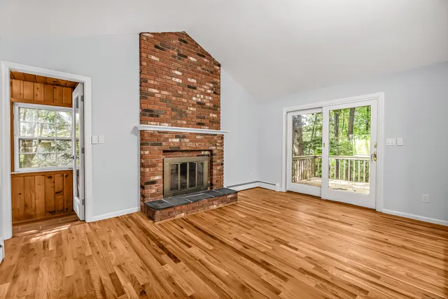 a view of empty room with wooden floor and fireplace