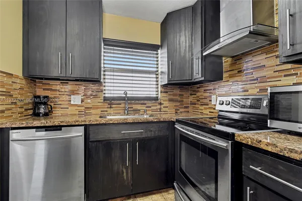 a kitchen with stainless steel appliances granite countertop wooden cabinets and a stove top oven