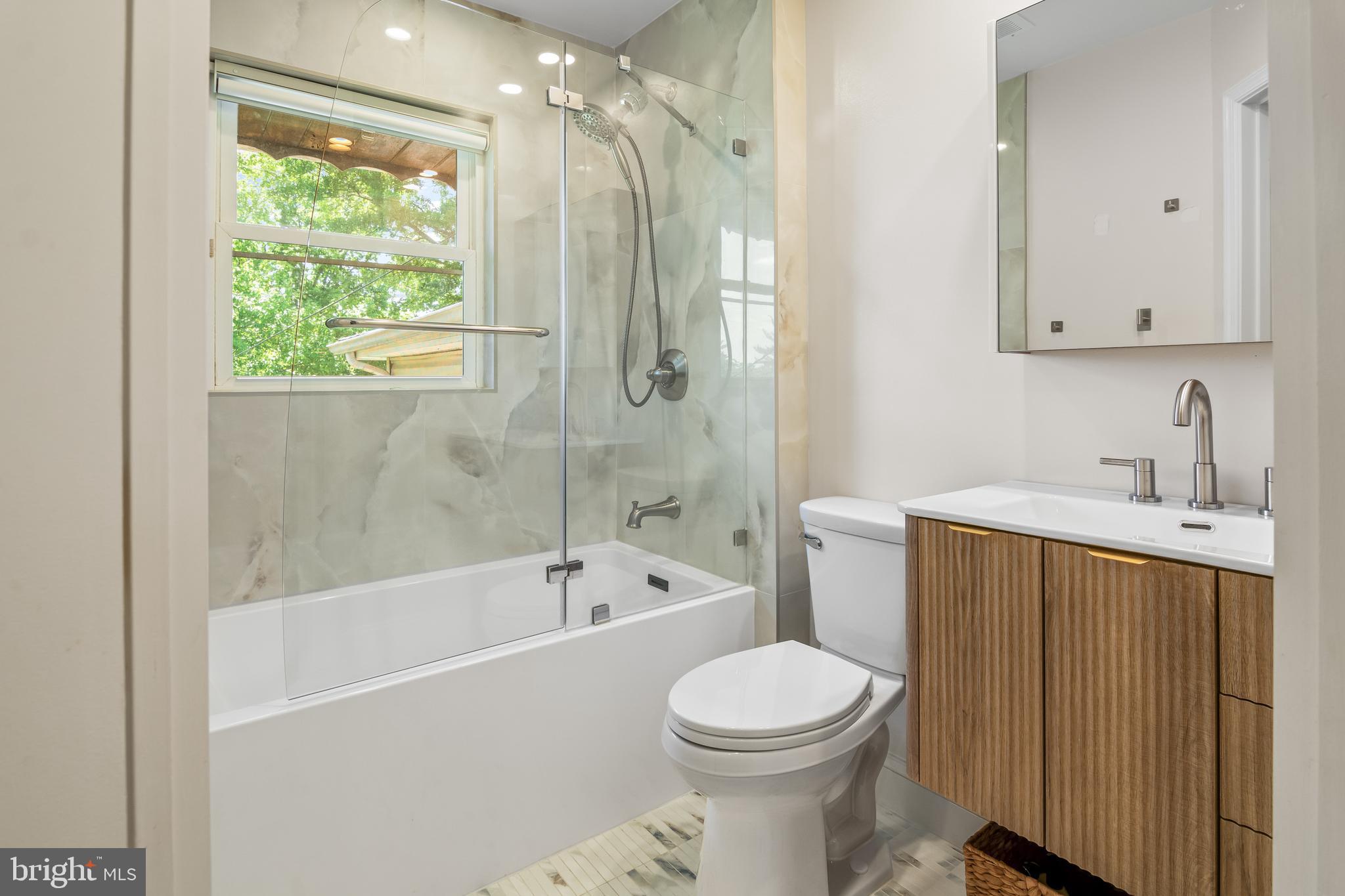 6308 Ivymount Road Baltimore, MD 21209 - Photo 14 of 22 a bathroom with a toilet a sink a mirror a bathtub and shower