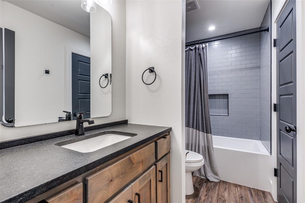 2687 North Trinity Street Decatur, TX 76234 - Photo 21 of 33 a bathroom with a granite countertop sink toilet a shower and a mirror