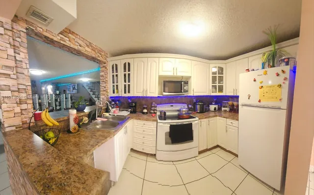 a kitchen with stainless steel appliances kitchen island granite countertop a refrigerator and a stove