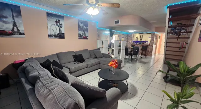 a living room with furniture a chandelier and kitchen view