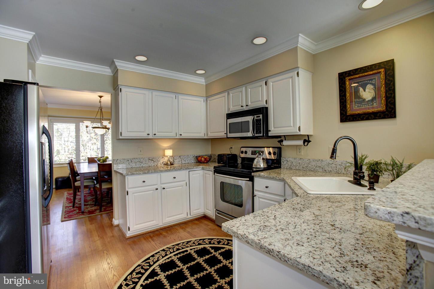 11632 Chapel Cross Way Reston, VA 20194 - Photo 15 of 30 a kitchen with stainless steel appliances granite countertop a sink stove refrigerator and wooden cabinets
