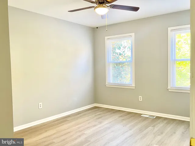 an empty room with windows and fan