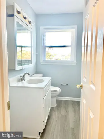 a bathroom with a granite countertop sink toilet and a window