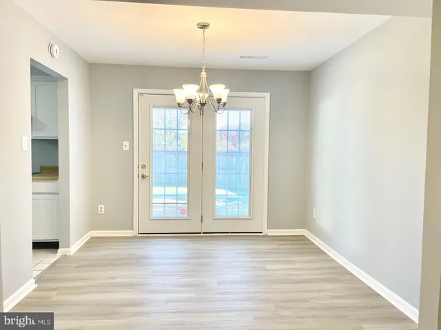 a view of an empty room with wooden floor and chandelier