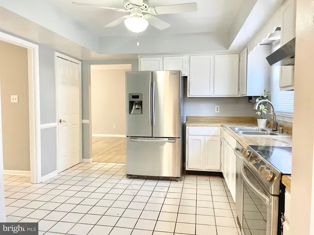 a kitchen with a stove a refrigerator and white cabinets
