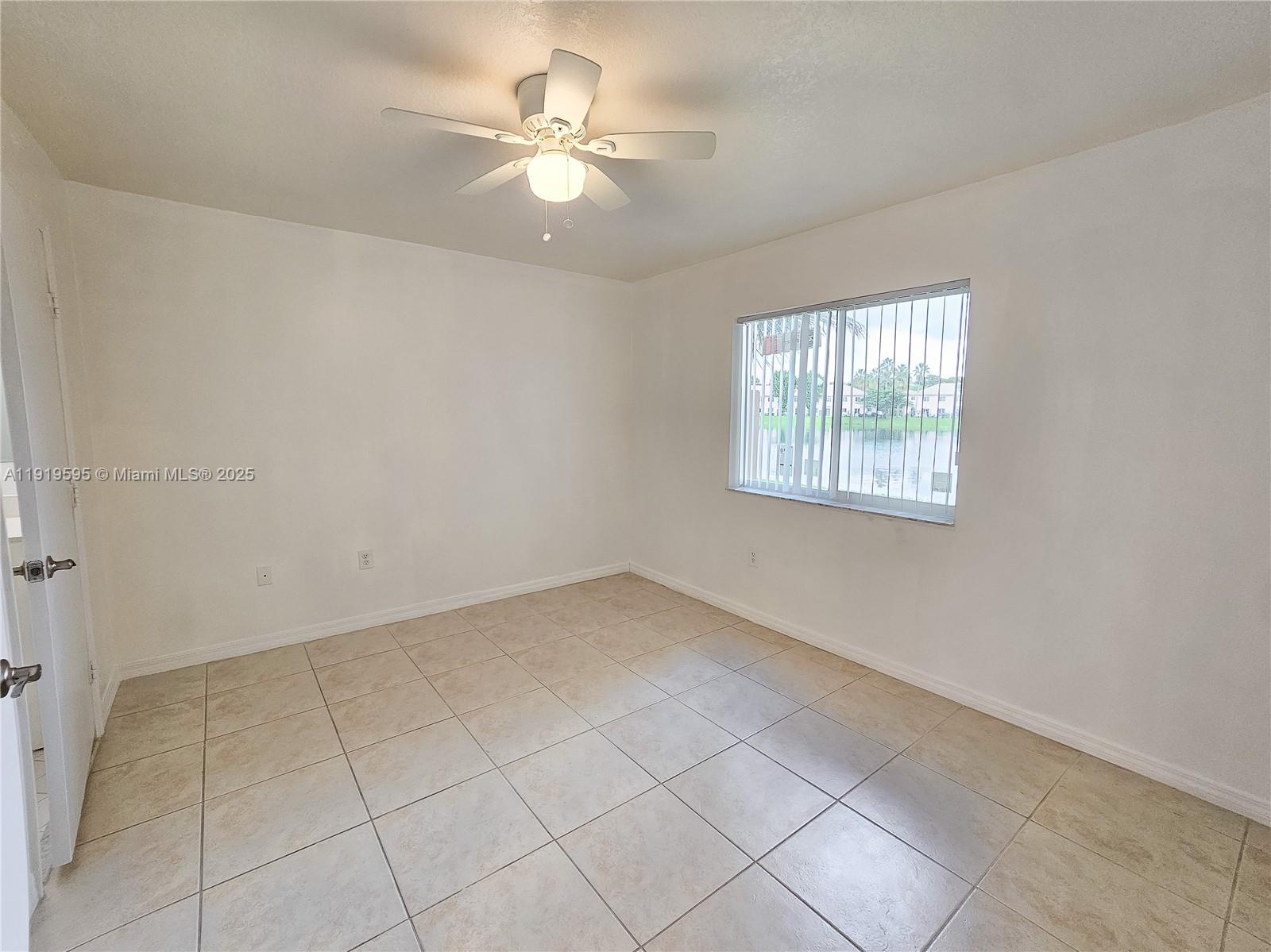 2651 Southeast 12th Road, Unit 105 Homestead, FL 33035 - Photo 18 of 24 an empty room with windows and chandelier fan