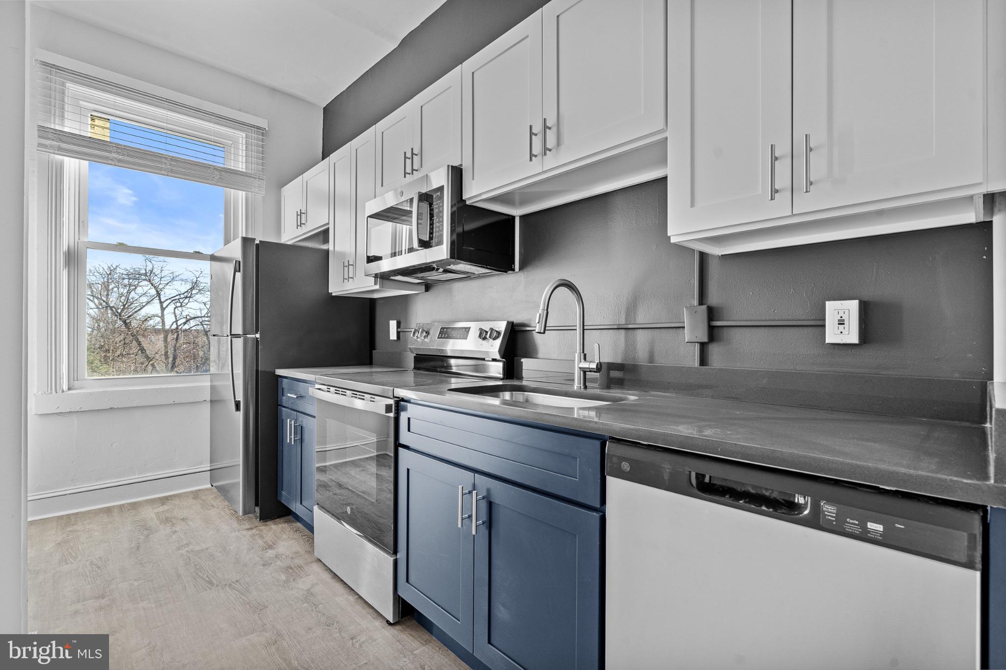 1308 West Lexington Street, Unit 3F Baltimore, MD 21223 - Photo 1 of 14 a kitchen with stainless steel appliances granite countertop a sink dishwasher a refrigerator and cabinets with wooden floor