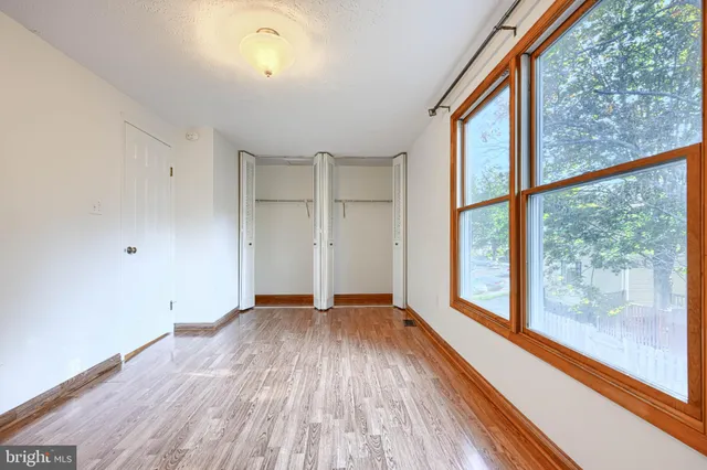 a view of empty room with wooden floor and fan