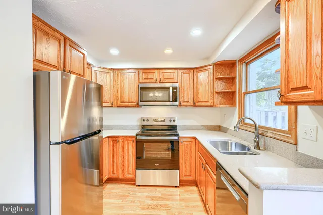 a kitchen with stainless steel appliances granite countertop a refrigerator a sink and a stove
