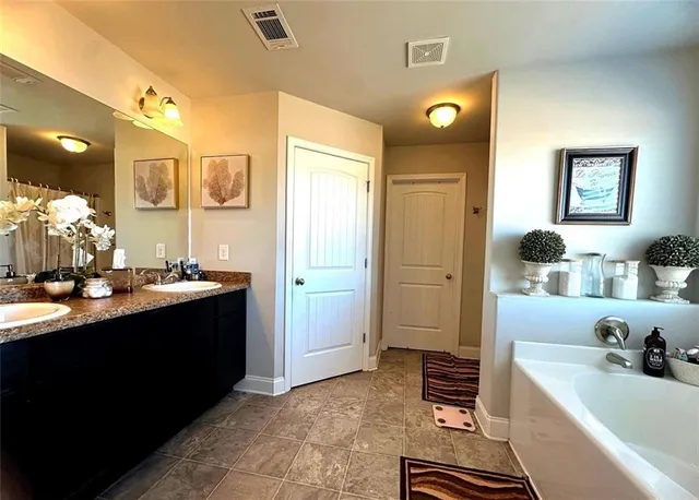 a bathroom with a sink vanity granite tub and a mirror