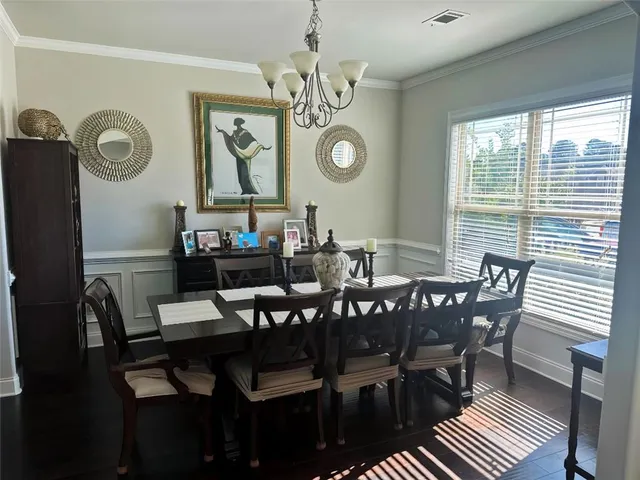 a view of a dining room with furniture a chandelier and a window