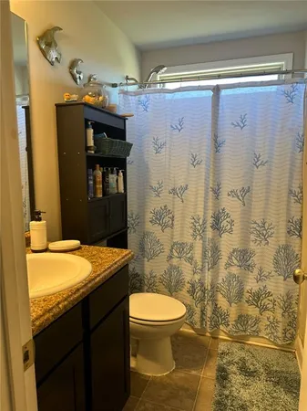 a bathroom with a granite countertop sink toilet and shower