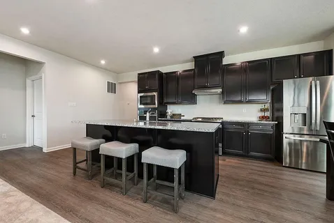 a kitchen with kitchen island granite countertop a sink counter and chairs