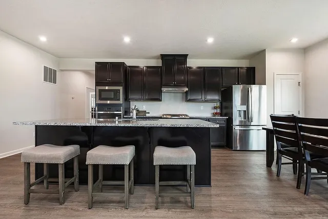 a kitchen with stainless steel appliances a table chairs refrigerator and microwave