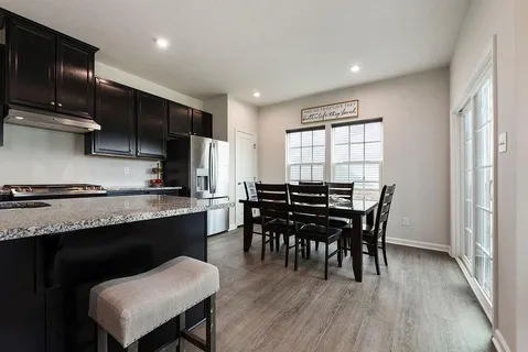 a kitchen with kitchen island a dining table chairs stainless steel appliances and cabinets