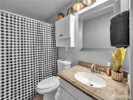 a bathroom with a granite countertop toilet sink and mirror