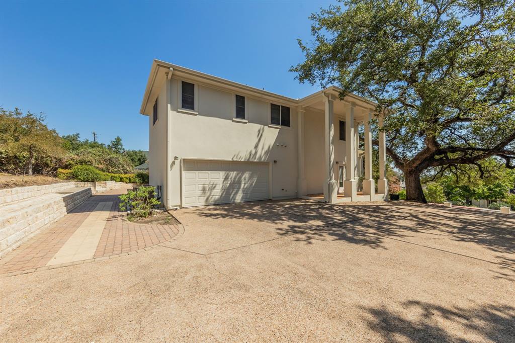1704 Randolph Ridge Trail Austin, TX 78746 - Photo 4 of 23 Back of house featuring an attached garage, stucco siding, and driveway