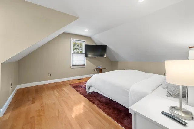 a spacious bedroom with a bed and wooden floor