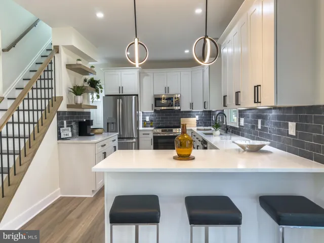 a kitchen with stainless steel appliances granite countertop a sink a stove a refrigerator cabinets and chairs