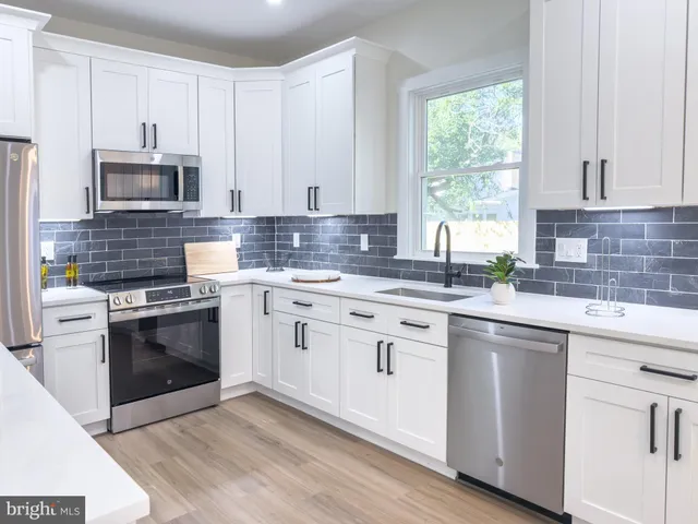 a kitchen with white cabinets sink and stainless steel appliances