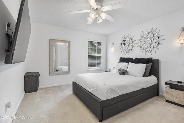 a large bedroom with a bed and a flat tv screen on a dresser