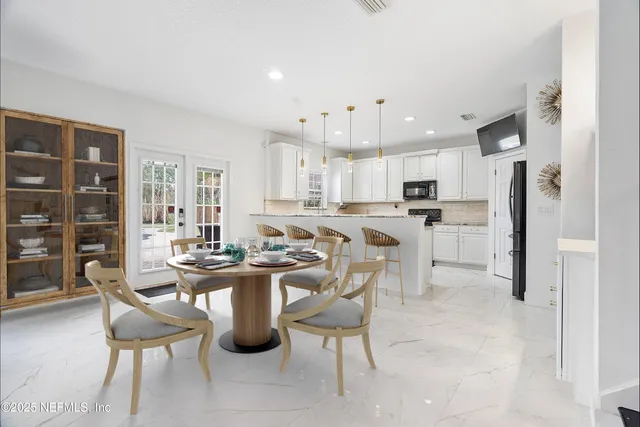 a kitchen with stainless steel appliances kitchen island granite countertop a table chairs refrigerator and microwave