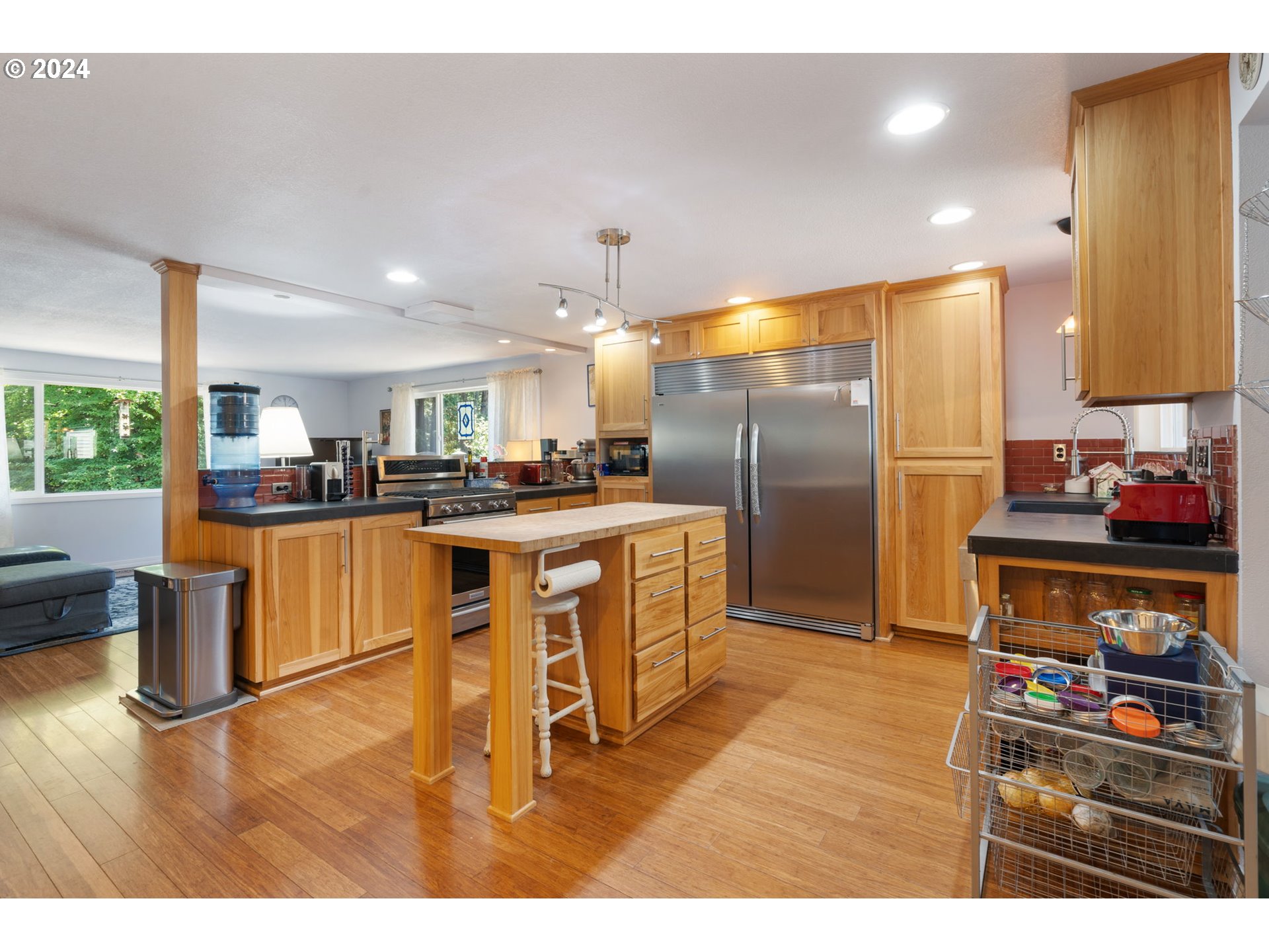 4409 Southwest Kanan Drive Portland, OR 97221 - Photo 3 of 25 a kitchen with stainless steel appliances kitchen island granite countertop a refrigerator a stove a sink and dishwasher with wooden floor