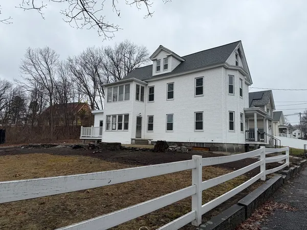 a view of a white house with a yard and large tree