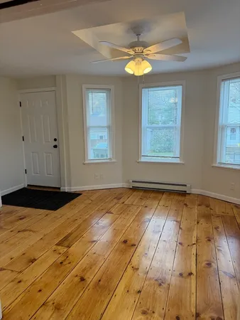a view of an empty room with window and wooden floor