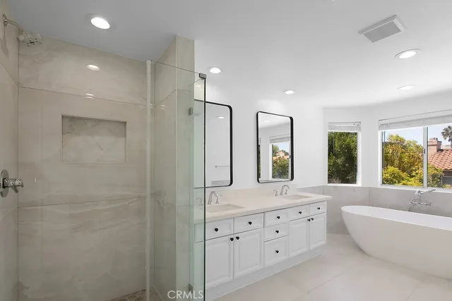 a bathroom with a bathtub a double vanity sink a large mirror a shower and a bathtub